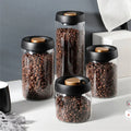 Vacuum-seal glass coffee canister with wood-grain lid on a kitchen counter
